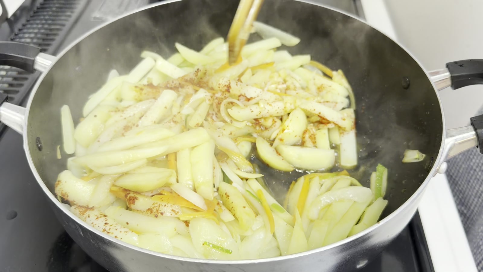 じゃがいもと野菜に調味料を加えて炒め合わせる様子